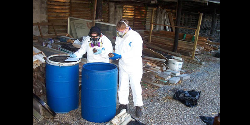 Two people in protective equipment removing pesticide